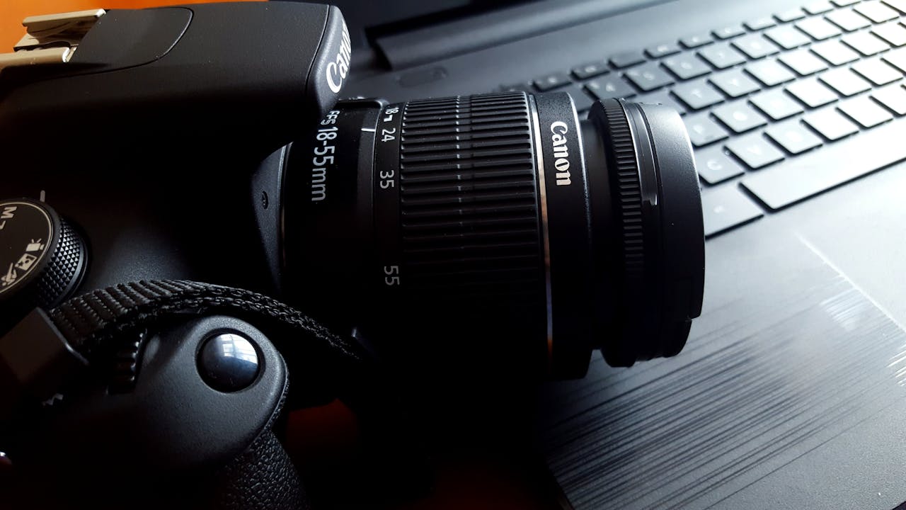 Close-up of a black DSLR camera with lens on a laptop keyboard.